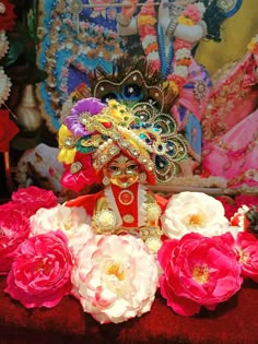 a statue with flowers in the foreground and a painting on the wall behind it