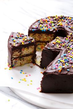 a chocolate cake with one slice cut out and sprinkles on the side