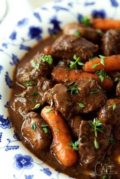 meat and carrots in gravy on a blue and white plate with flowers