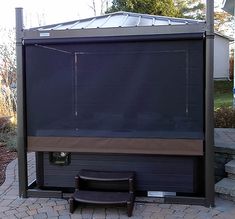 a bench sitting in front of a covered gazebo on a brick walkway next to a house