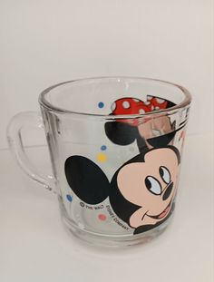 a mickey mouse glass mug with polka dots on it