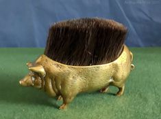 a golden boar brush holder on green grass