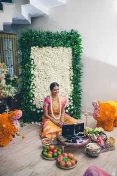 a woman sitting on the floor in front of flowers and decorations with a laptop computer