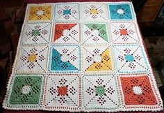 a crocheted blanket that has been made with squares and stars on it, sitting on top of a table