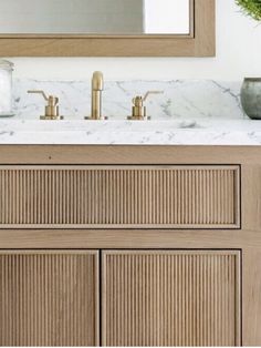 a bathroom vanity with marble counter top and wooden cabinetry, along with a large mirror above it