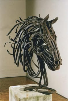 a metal horse head sitting on top of a block of wood next to a wall