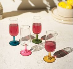 five wine glasses sitting on top of a table next to each other with different colored liquids in them