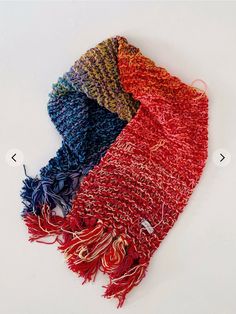 four different colors of knitted scarves on a white surface