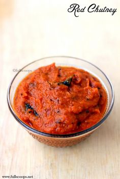 a bowl filled with red sauce on top of a wooden table