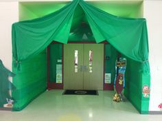 a large green tent in the middle of a room with two doors and some signs on it