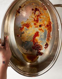 a person holding a metal pan with food in it on top of a white counter