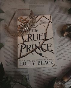 the cruel prince by holly black on top of an open book surrounded by leaves and other items