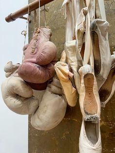 several pairs of ballet shoes hanging on a wall next to each other, with one worn shoe in the foreground