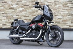 a black motorcycle parked in front of a brick wall with no one sitting on it