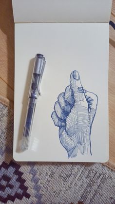 a pen sitting on top of a piece of paper next to a drawing of a hand