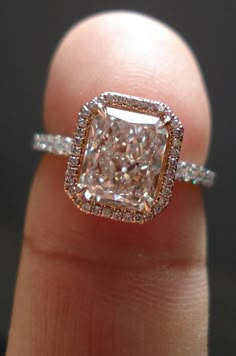 a close up of a person's hand holding an engagement ring