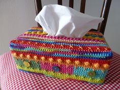 a colorful crocheted tissue box sitting on top of a checkered table cloth