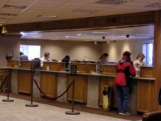 people are standing at the front desk of a hotel or motel lobby, waiting for their luggage