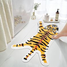 a tiger rug is being held up by someone's hand on the bathroom counter