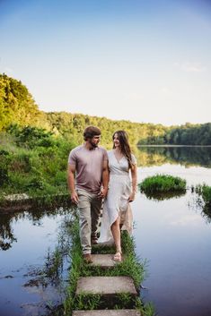 a man and woman walking across a bridge over water