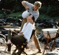 two men are sitting in chairs and one man is holding a white ball over his head