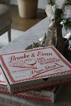 two pizza boxes sitting on top of a table next to a vase with white flowers