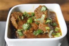 a white bowl filled with meat and vegetables