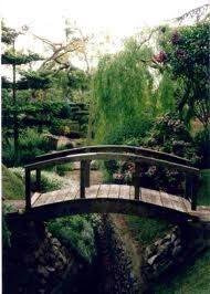 a wooden bridge over a small pond in a park