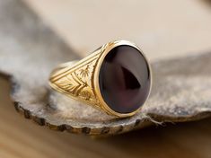 A beautiful signet ring with carvings on the sides made by hand and garnet gemstone in the center. *real images of the ring, taken by us* Garnet Stone Size: 14x12mm Material: - Sterling Silver 925 - 9K Gold (375) - 14K Gold (585) - 18K Gold (750) *All signet rings are hallmarked on the back for certification* - We offer FREE Worldwide DHL & FedEx Shipping! - Branded DanelianJewelry Gift Box with each order! Our customer service is available 7 days a week. Leave us your message, and we will get b Heirloom Signet Ring With Cabochon As A Gift, Heirloom Signet Ring With Cabochon For Gift, Oval Ruby Intaglio Ring For Anniversary, Engraved Ruby Ring For Collectors, Collectible Engraved Ruby Ring, Antique Carved Signet Ring, Antique Ruby Signet Ring, Oval Carved Signet Ring For Anniversary, Formal Garnet Signet Ring