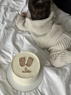 a baby's foot prints on a cake next to a white sheeted bed