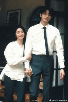 a man and woman standing next to each other in front of a doorway holding hands