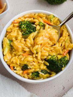 a bowl filled with pasta and broccoli on top of a white tablecloth