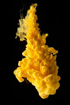 a yellow substance floating in the air on a black background with space for text or image