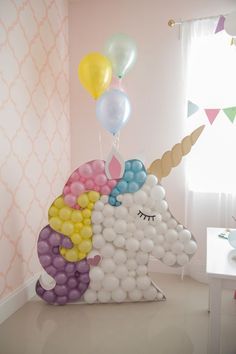 an inflatable unicorn with balloons on its head is sitting next to a table