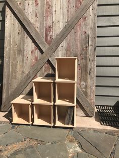 a set of four wooden shelves sitting on top of a stone floor next to a barn door