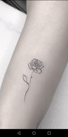 a black and white rose tattoo on the left arm, with a single line drawing