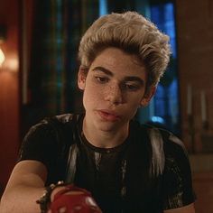 a young man sitting at a table with an apple in his hand