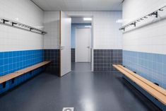 an empty bathroom with blue and white tiles on the walls, benches in front of the door