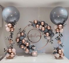 two balloons and some decorations on a table with silver, pink and gold balls in the middle