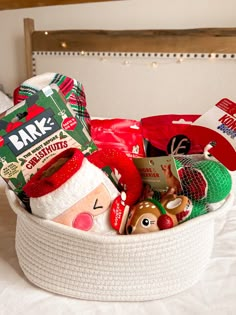 a white basket filled with christmas items on top of a bed