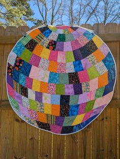 a colorful patchwork quilt hanging from a wooden fence