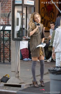 a woman is standing on the street talking on her cell phone