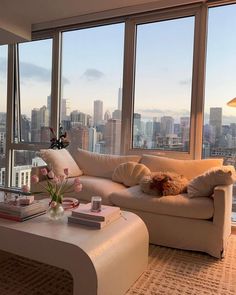 a living room filled with furniture and large windows overlooking the cityscape in the distance