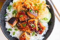 a bowl filled with rice, meat and veggies next to chopsticks