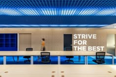 an empty conference room with blue lighting on the ceiling and people walking in the background