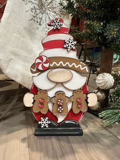 a christmas decoration with a santa clause and gingerbreads on the bottom, in front of a tree