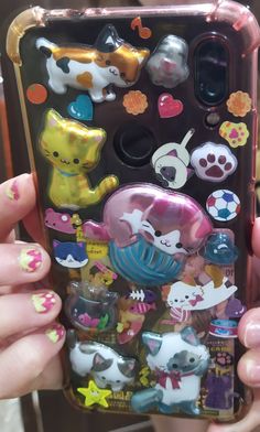 someone holding up their cell phone case with many stickers on the front and back