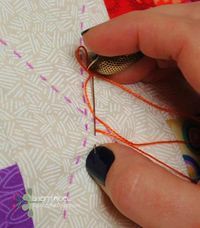 someone is sewing something on a piece of fabric with some scissors and thread in their hand