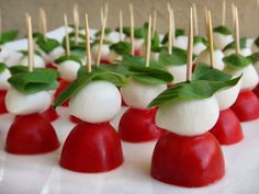 small appetizers with green leaves on them sit on a white plate