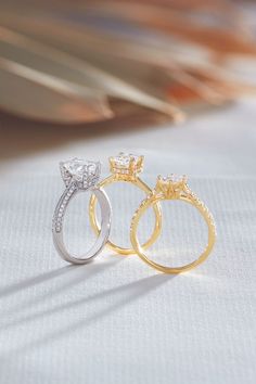 two gold and silver wedding rings with diamond accents on white fabric, close - up